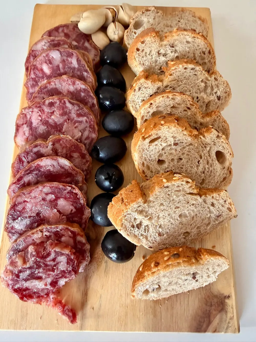 Tabla con salchichón cular ibérico de bellota en rodajas, pan y aceitunas